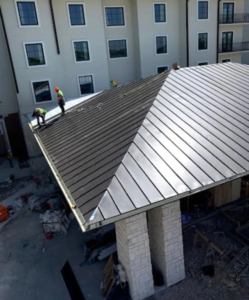 Crew installing standing seam metal roof panels on a commercial project in Warwick